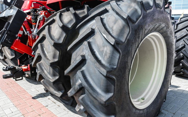 Close-up of tractor tires with deep treads on a brick path.