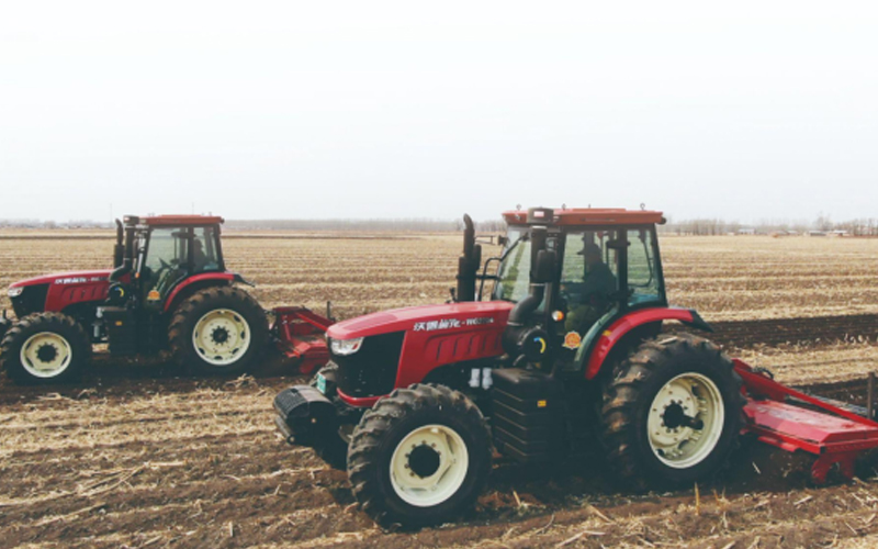 Two FM World tractors are plowing the field.