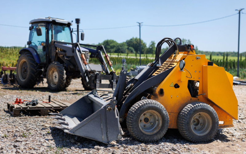 A small tractor with a bucket for moving soil, turf and bulk materials